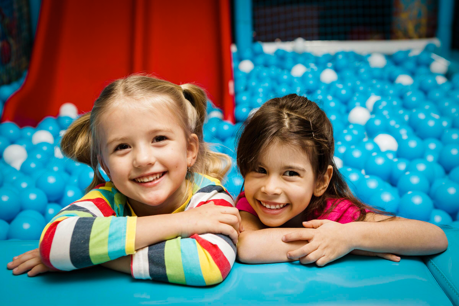 Two little girls laughing having fun in a sensory ball pit