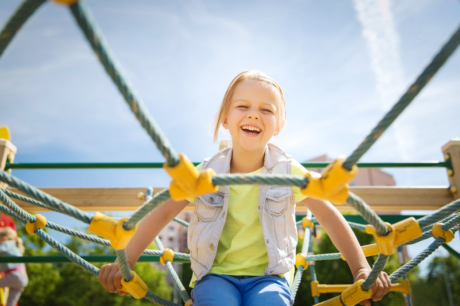 A little girl having fun and laughing while playing on an outdoor play set