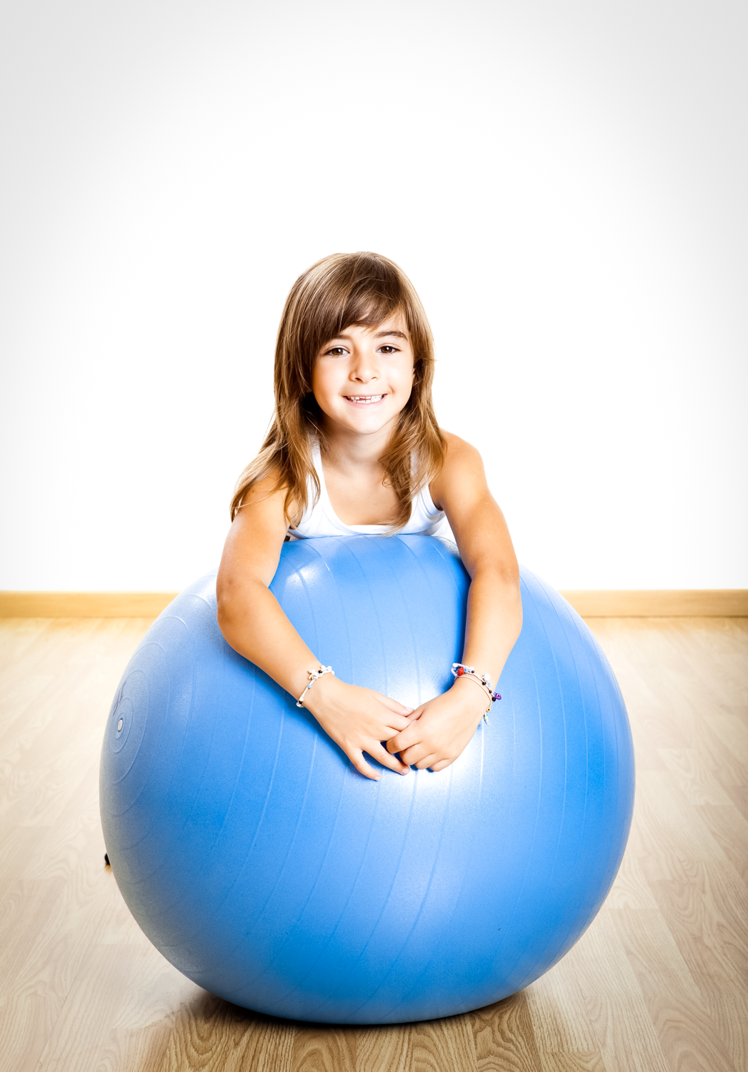 A little girl leaning on a medicine ball