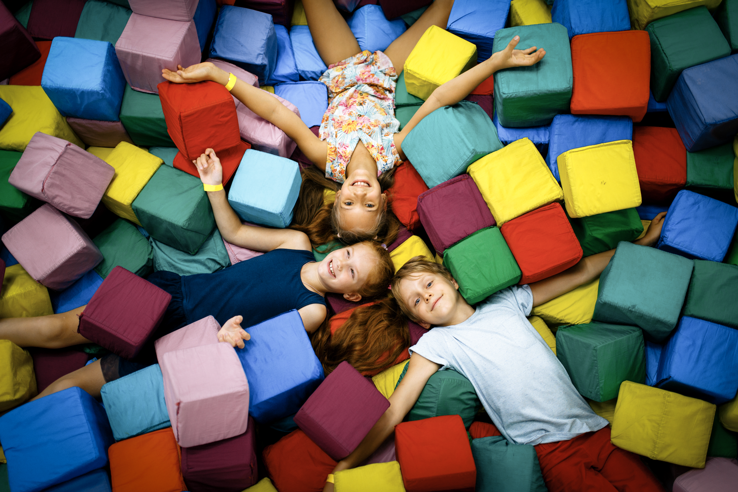 Three little girls laying on their backs appearing to be exhausted, but smiling, in a sensory pit