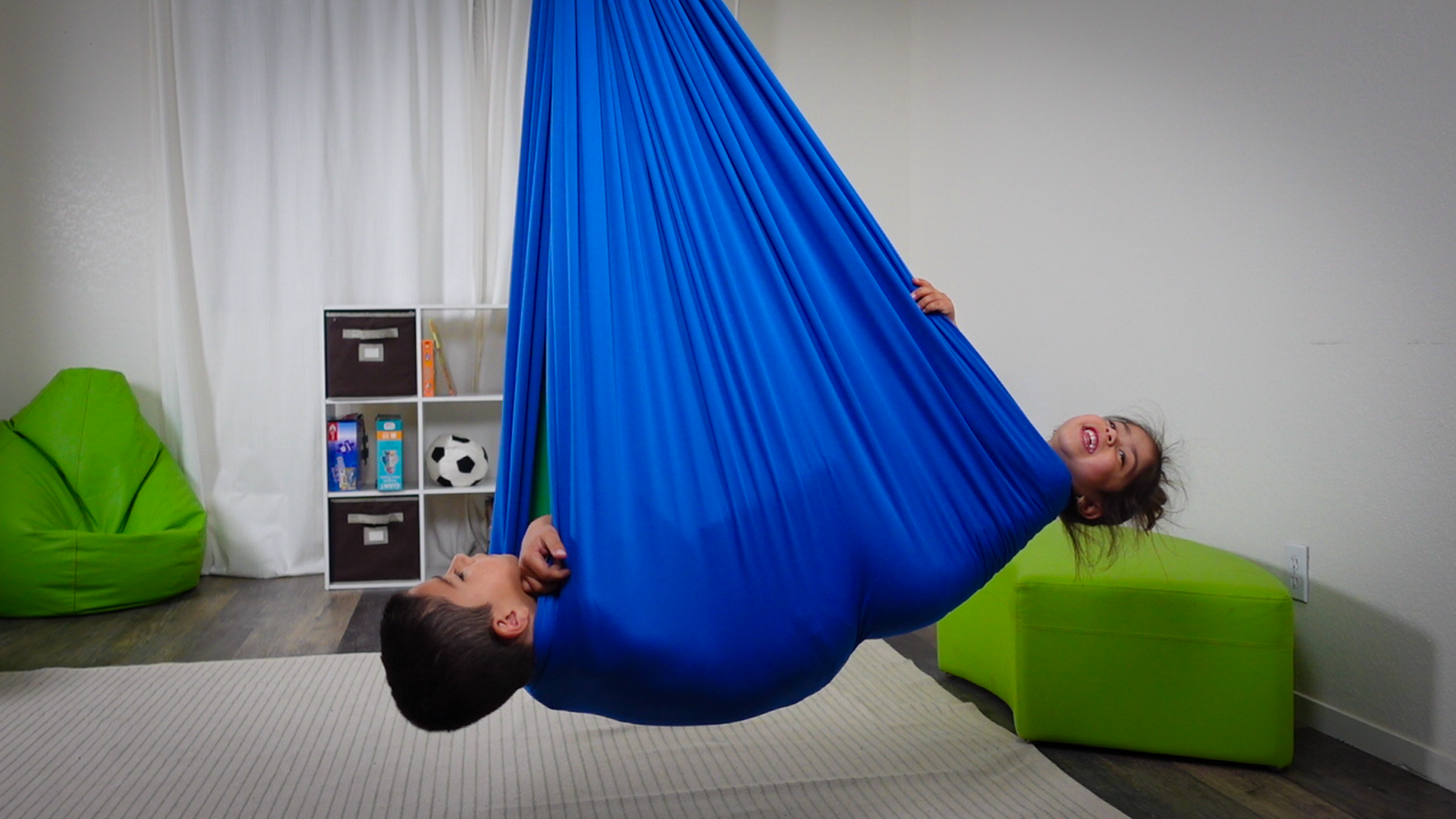 Siblings swinging together in a compression swing